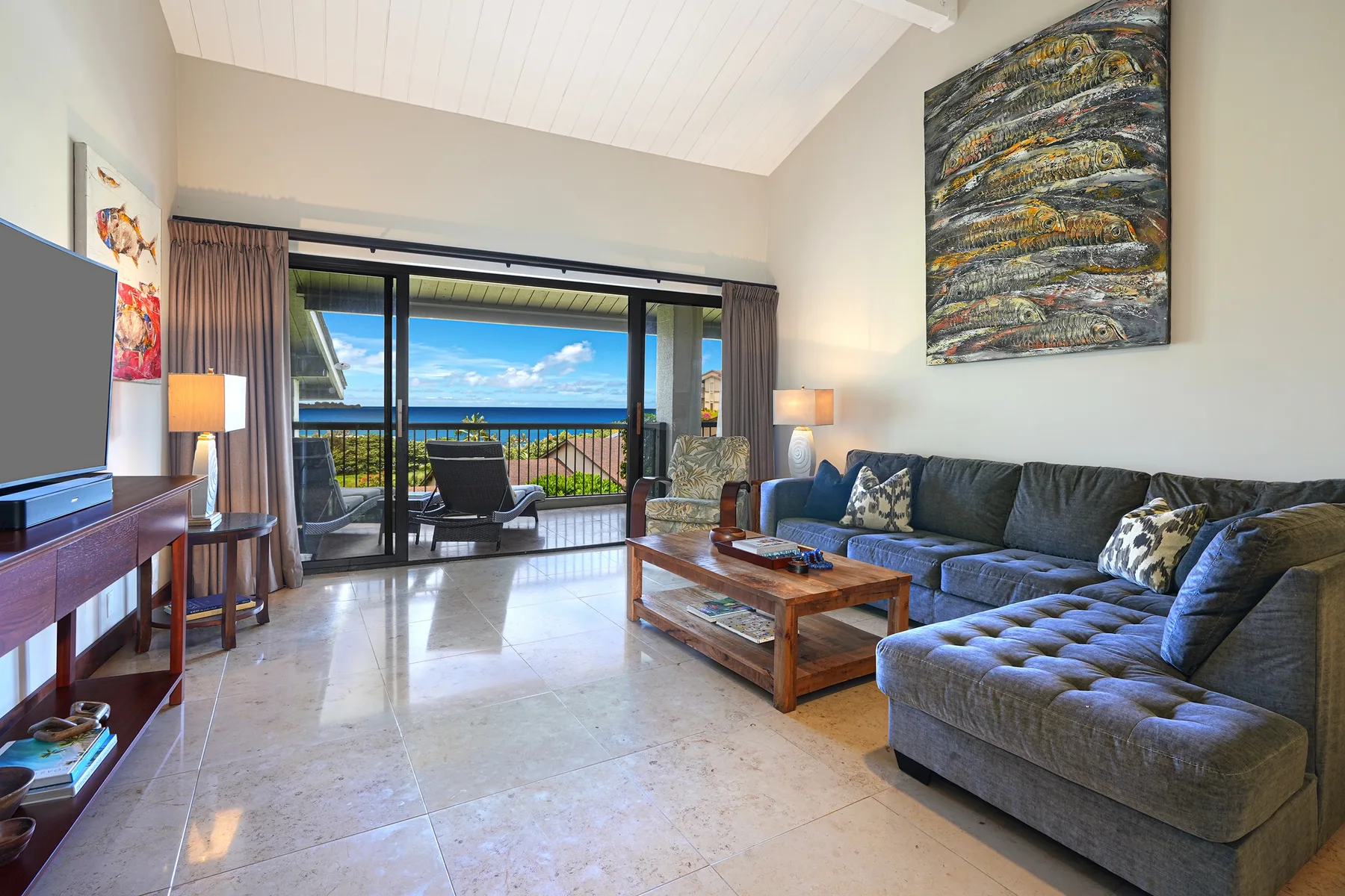 A living room with gray seating and sliding glass doors opening to a balcony.