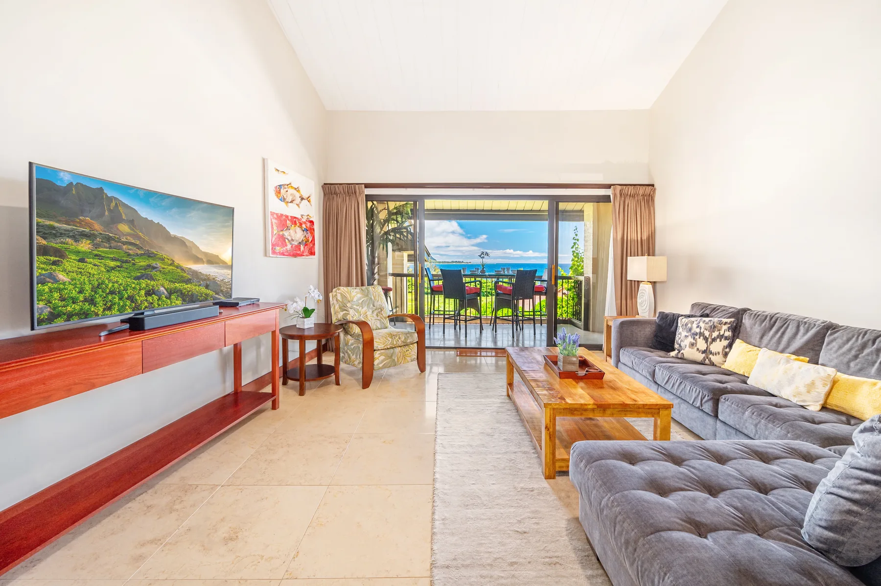 A bright living room opens onto a balcony with ocean views.
