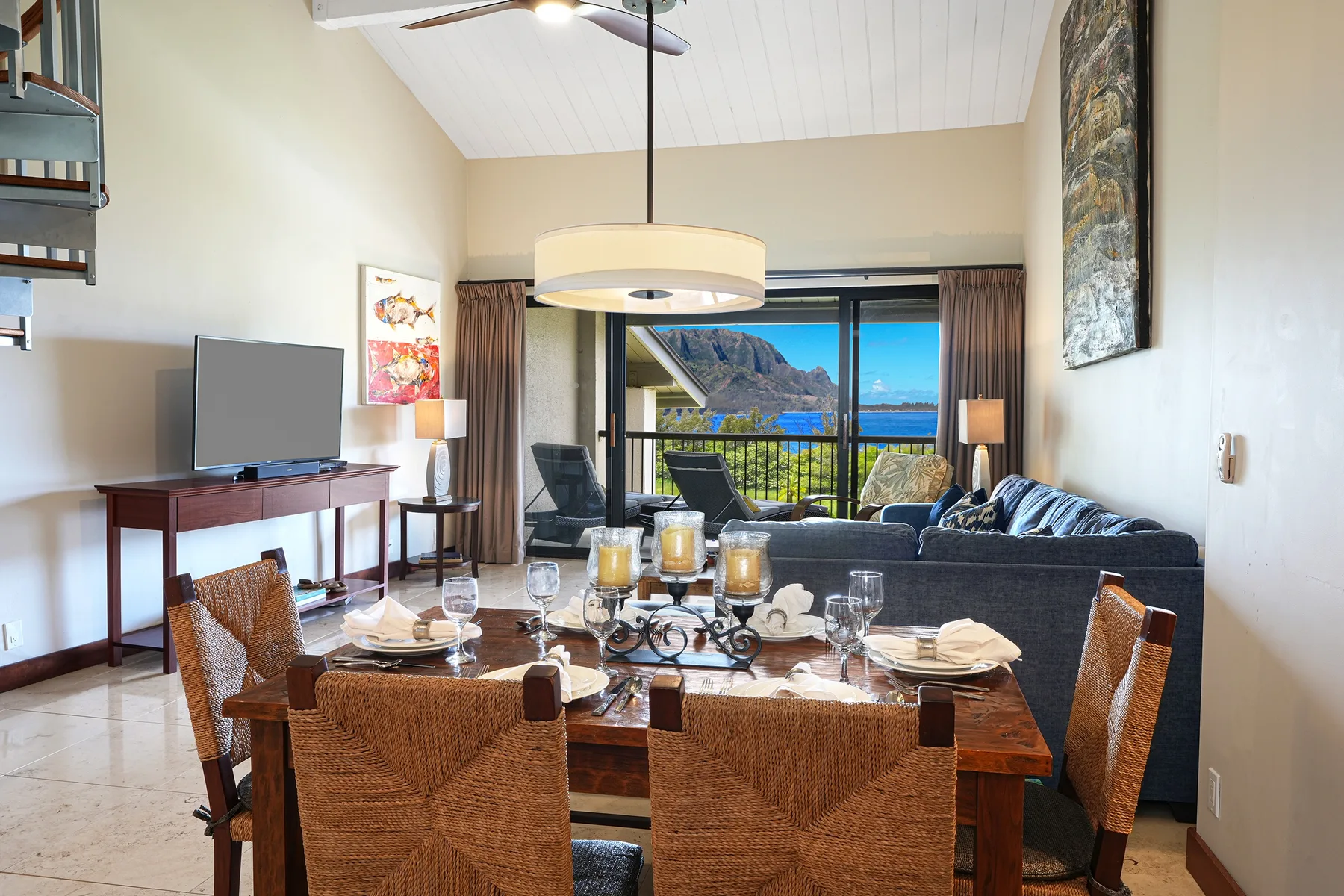 A living and dining area with a table, seating, and a large window overlooking the water.