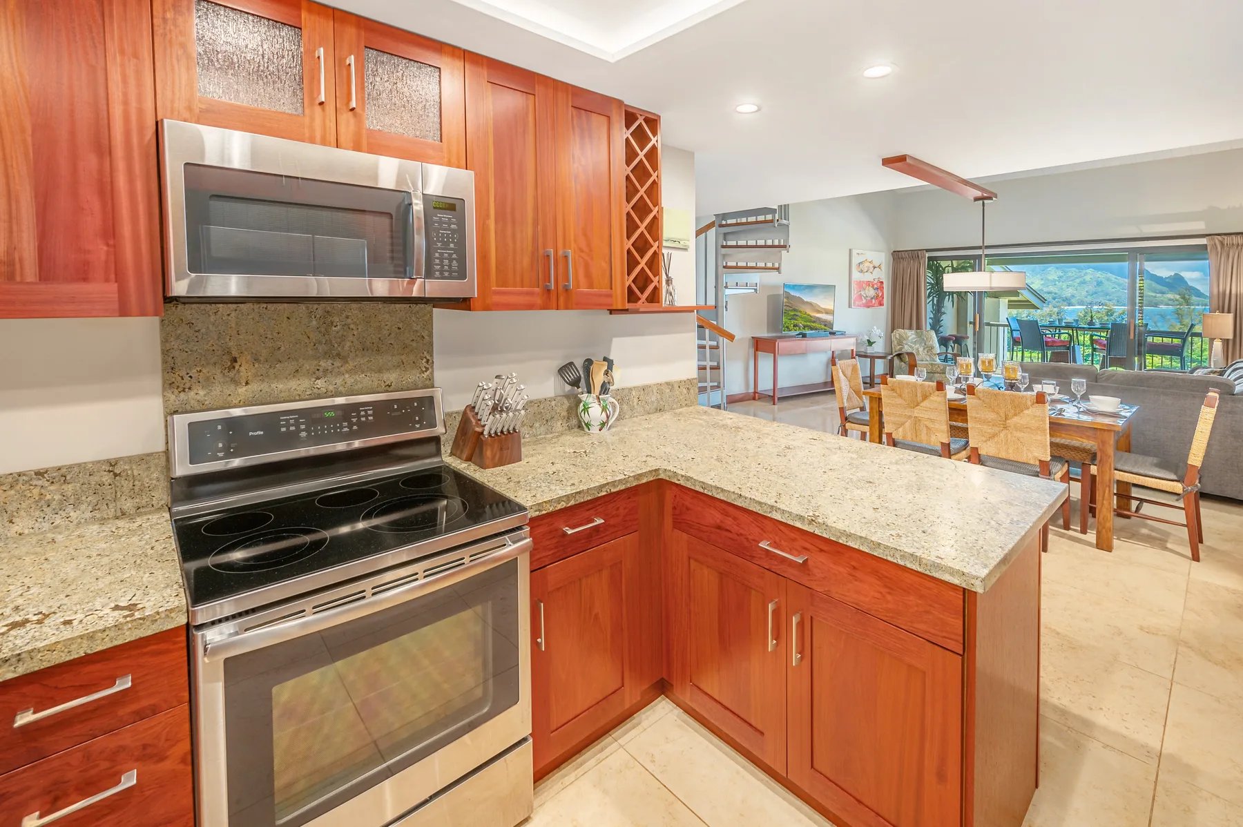 A kitchen with wooden cabinets and a central island opens onto a dining area.