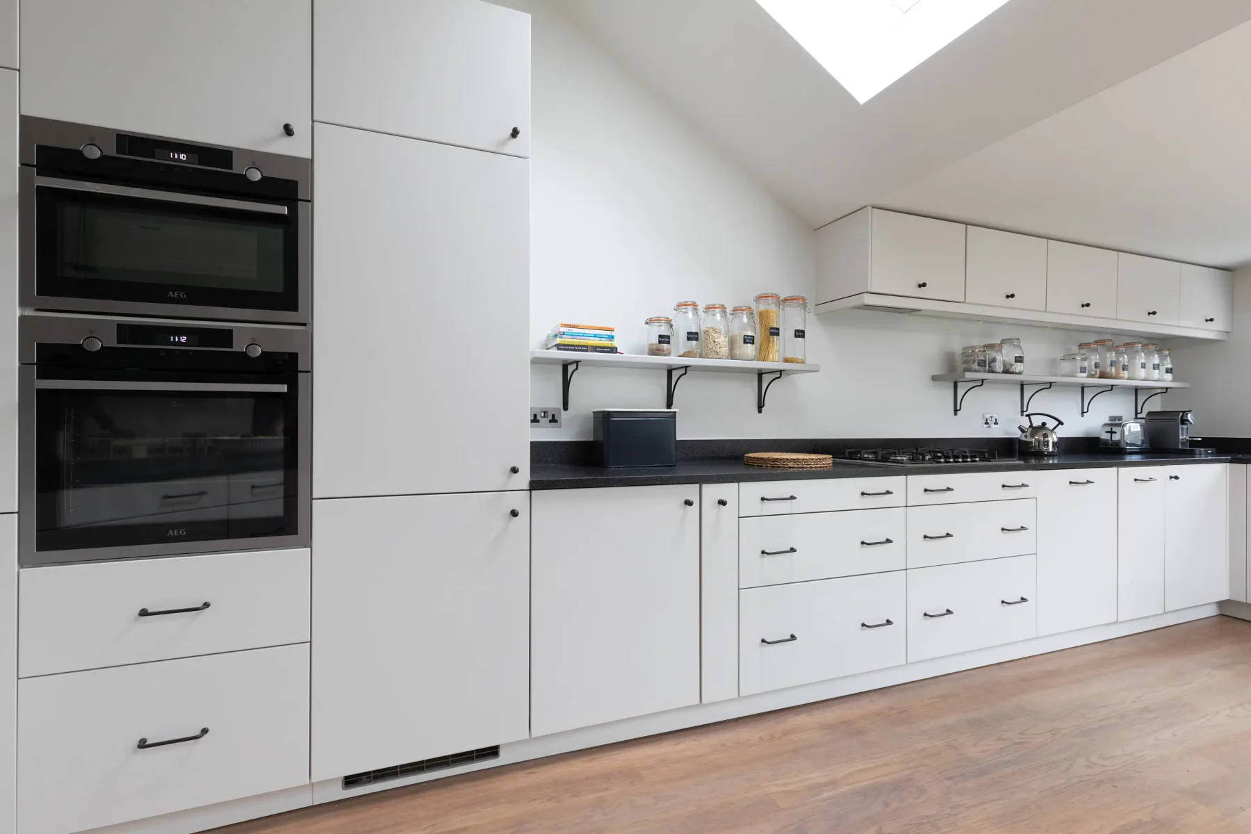 Una cocina moderna y luminosa con armarios blancos y una encimera oscura.
