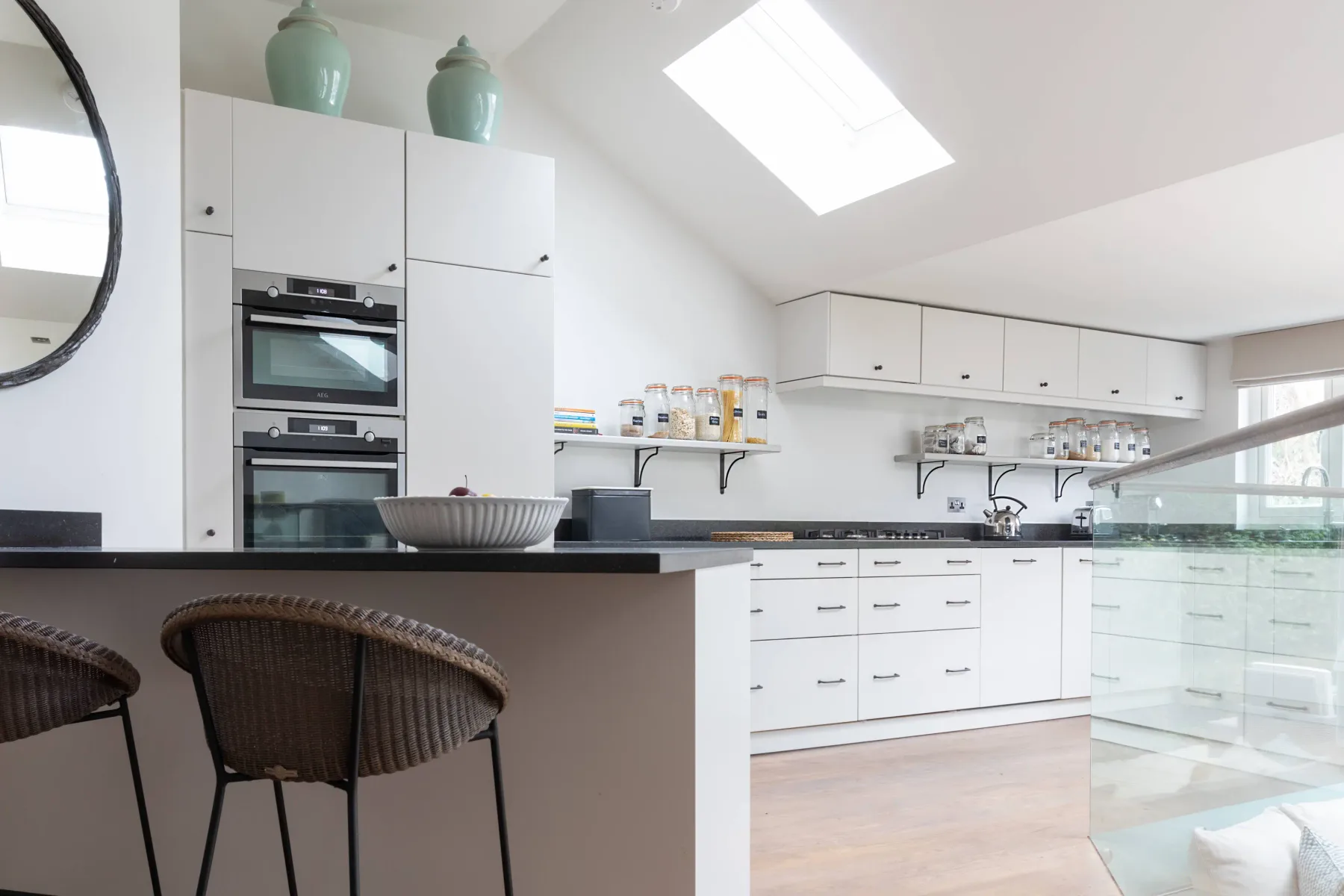 Una cocina moderna y luminosa con gabinetes blancos, una isla central y una claraboya.