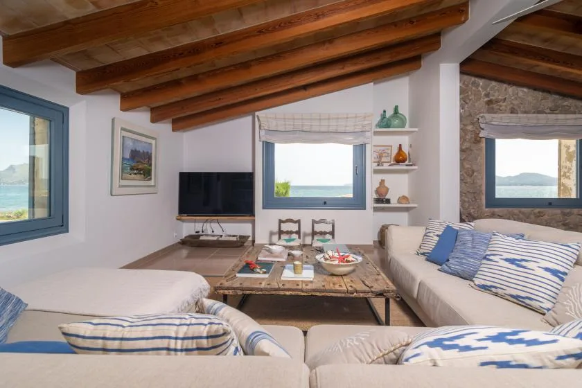 A bright living room with seating, a coffee table, and exposed wooden ceiling beams.