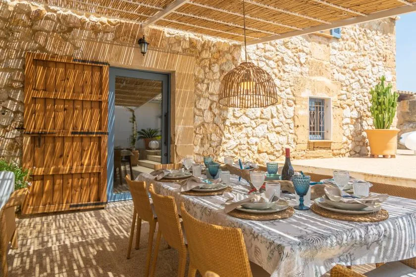 A shaded outdoor dining area with a set table beneath a reed canopy.