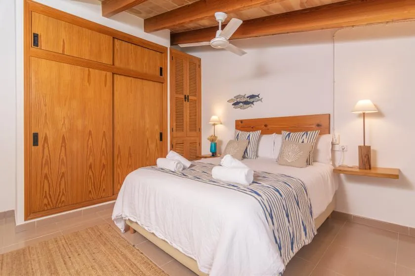 A bedroom with a neatly made bed and wooden built-in wardrobes.