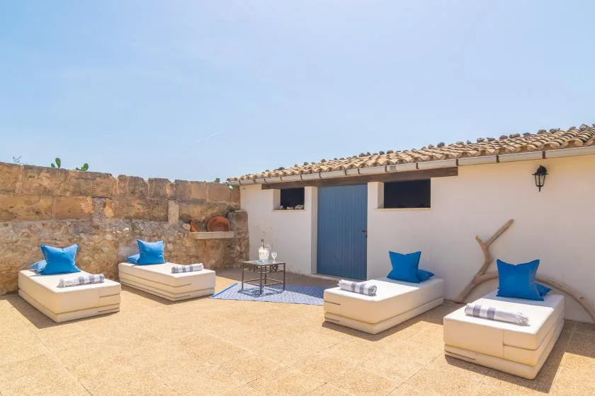 A sunny outdoor patio with cushioned seating and a blue door.