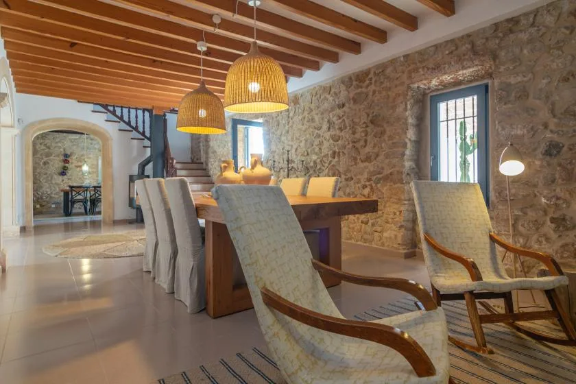 A dining area with a long wooden table, upholstered seating, and exposed ceiling beams.