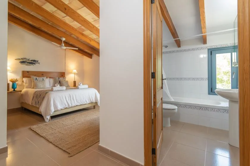 A bedroom with a bed beside an open bathroom.