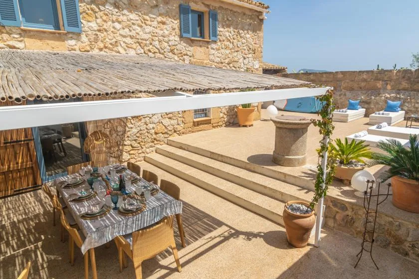 A stone terrace has a shaded dining area, broad steps, and a central stone table.