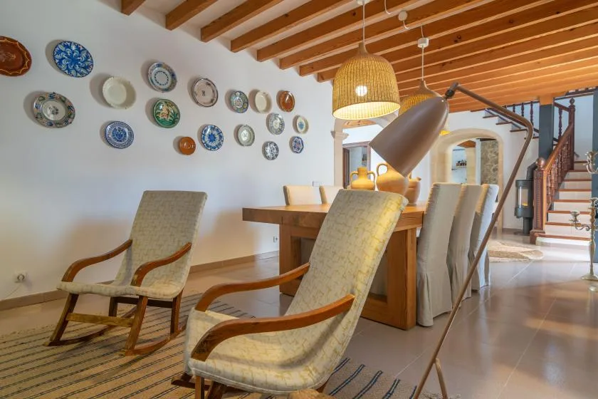 A dining area with a wooden table, upholstered seating, and decorative plates on the wall.
