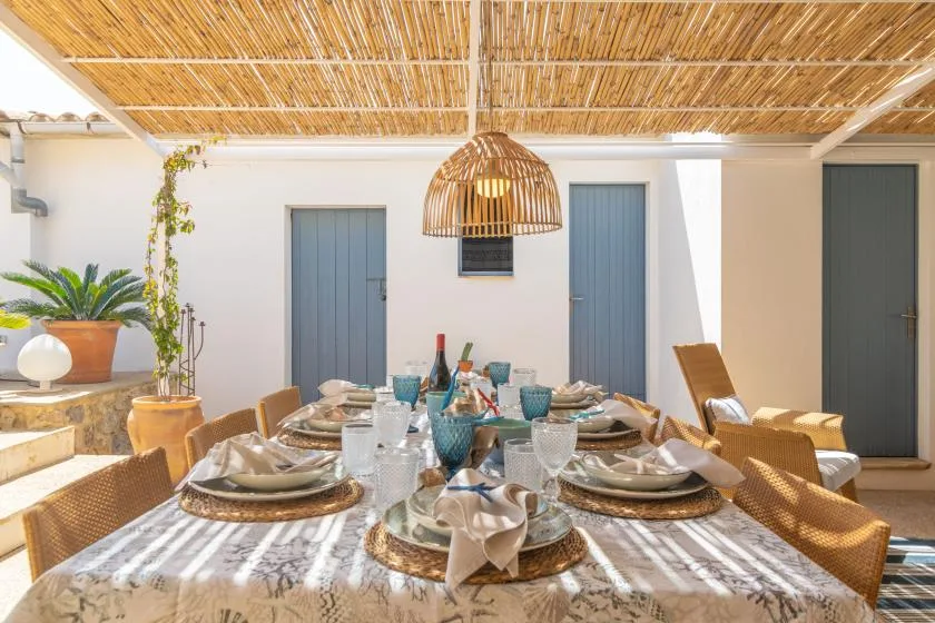 An outdoor dining area with a set table beneath a reed canopy.