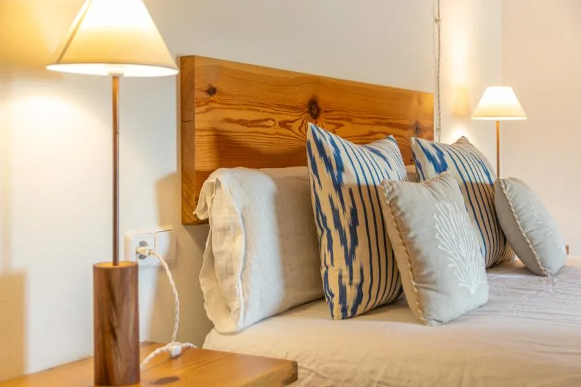 A bedroom with a wooden headboard and pillows arranged on the bed.