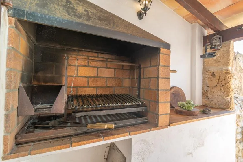 A brick barbecue grill is set into a kitchen wall beside a stone counter.