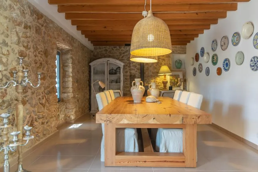 A dining room with a long wooden table beneath a woven pendant lamp.