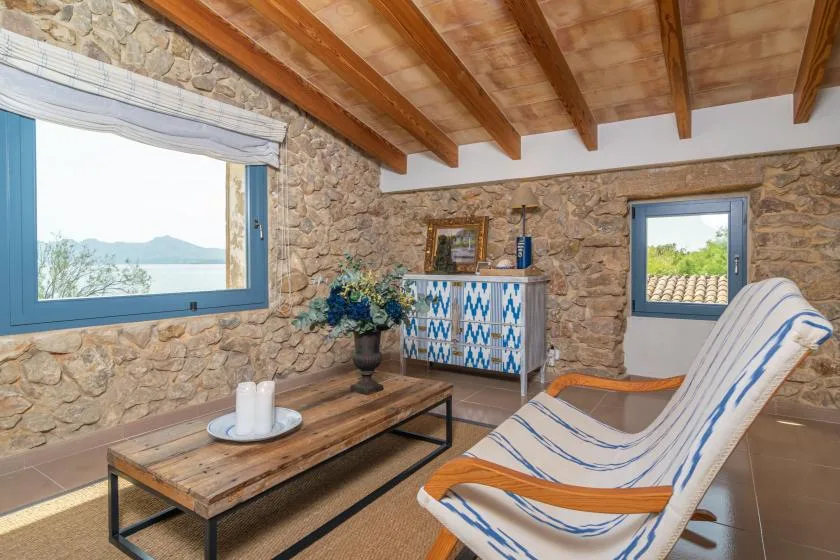 A stone-walled sitting room with a low table and striped lounge seating.