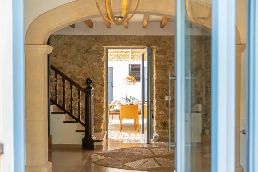 A stone-walled entryway opens onto a dining area, with a staircase along one side.