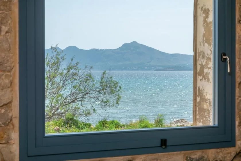 A window frames a view of a lake, shoreline vegetation, and distant mountains.
