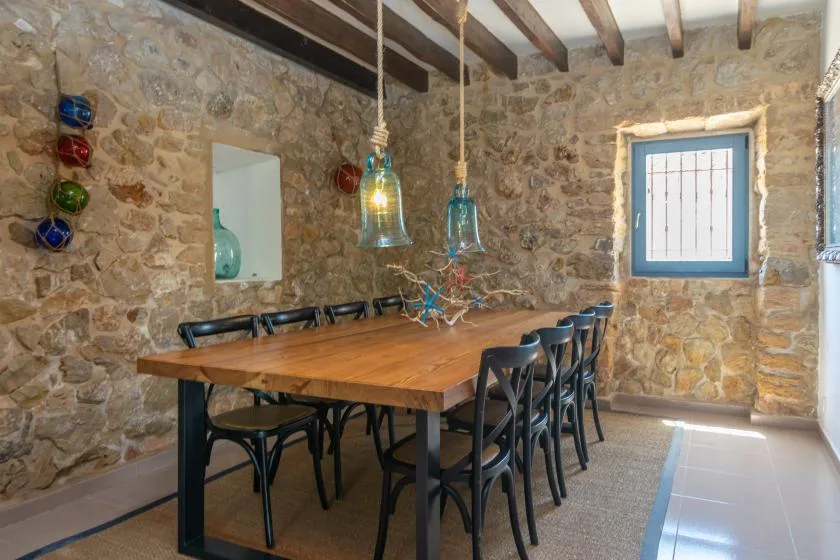 A dining area with a wooden table and chairs against stone walls.