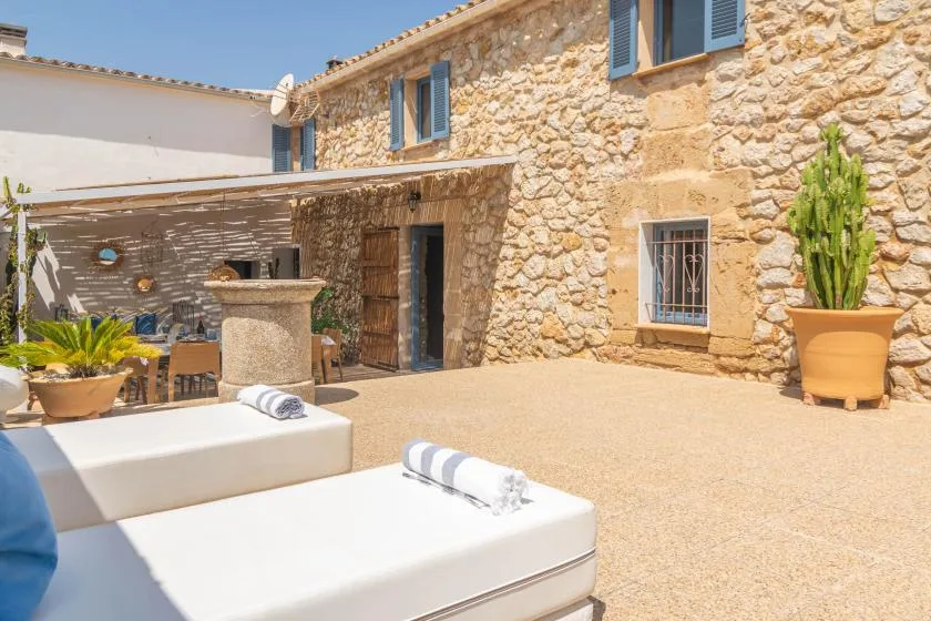 A sunny stone courtyard with lounge seating and a shaded dining area.