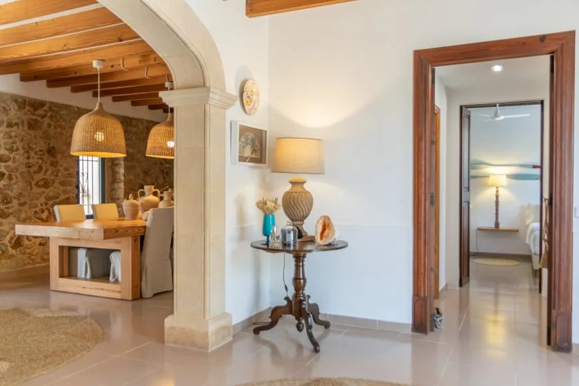 A bright interior connects a dining area with a hallway leading to a bedroom.