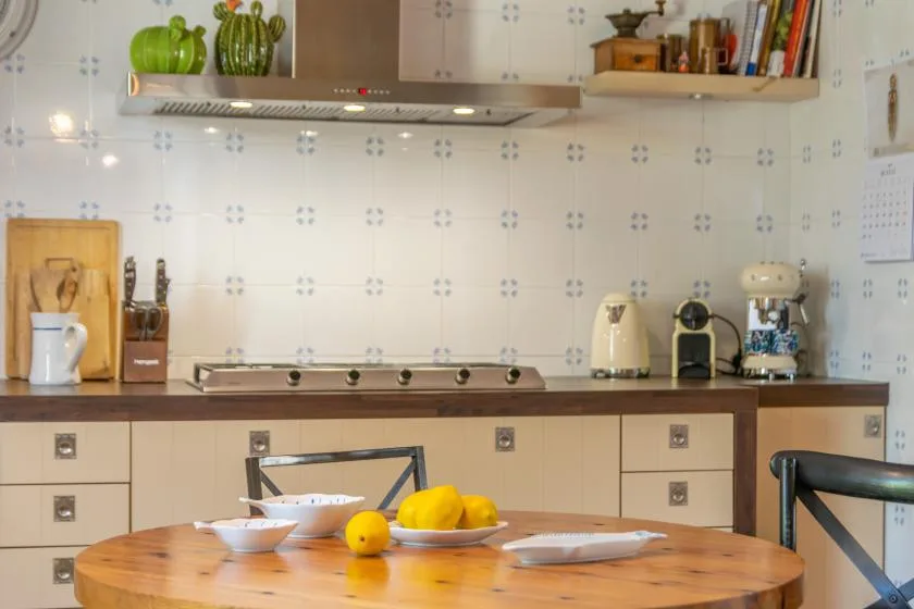 A tiled kitchen with a wooden table and small appliances along the counter.