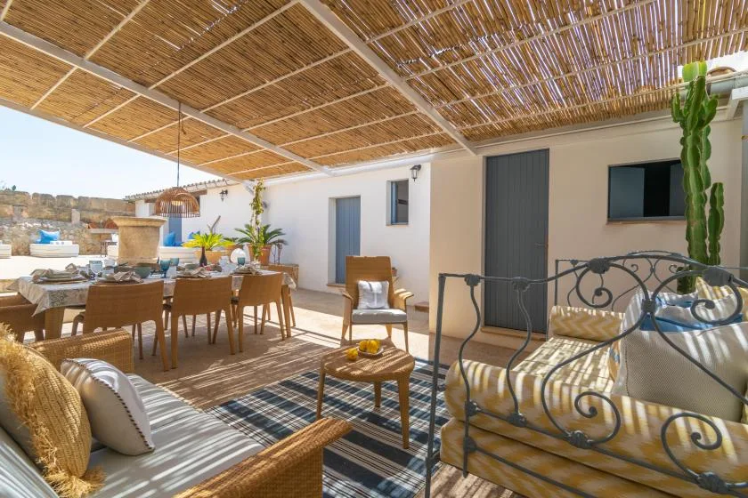 A shaded outdoor dining and seating area sits beneath a woven canopy.