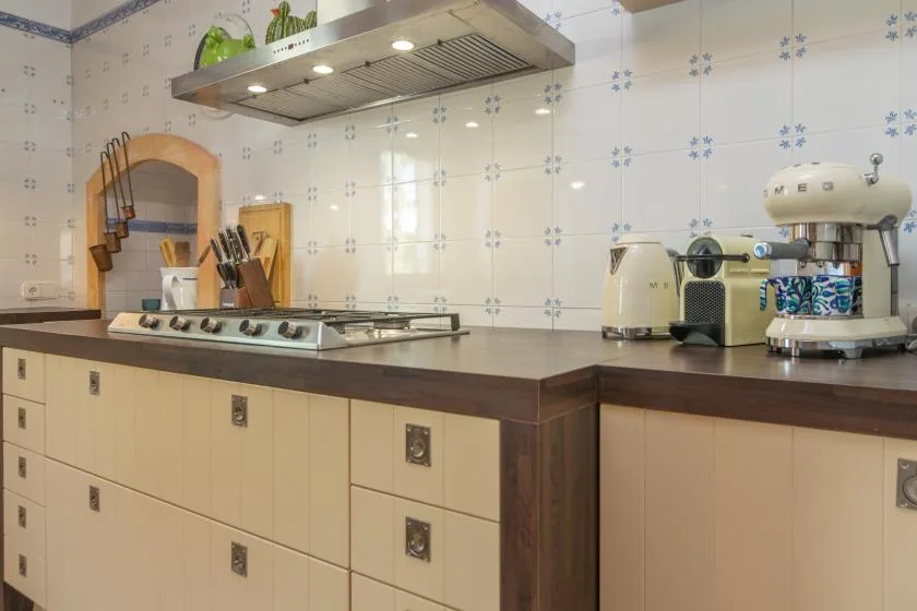 A tiled kitchen with a long counter, stovetop, and small appliances.