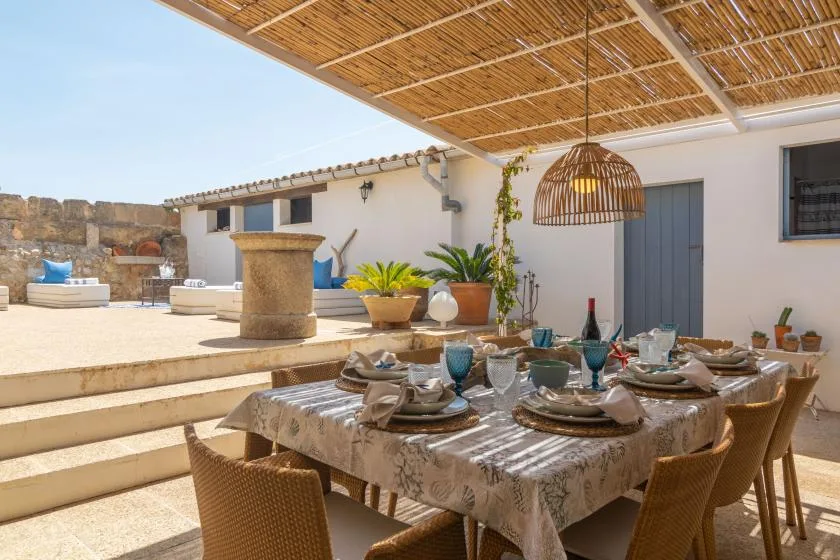 A shaded outdoor dining area with a set table beneath a reed canopy.