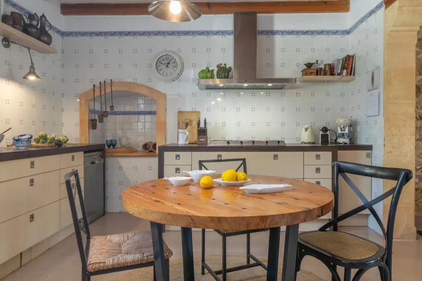 A tiled kitchen with a round wooden dining table and chairs.