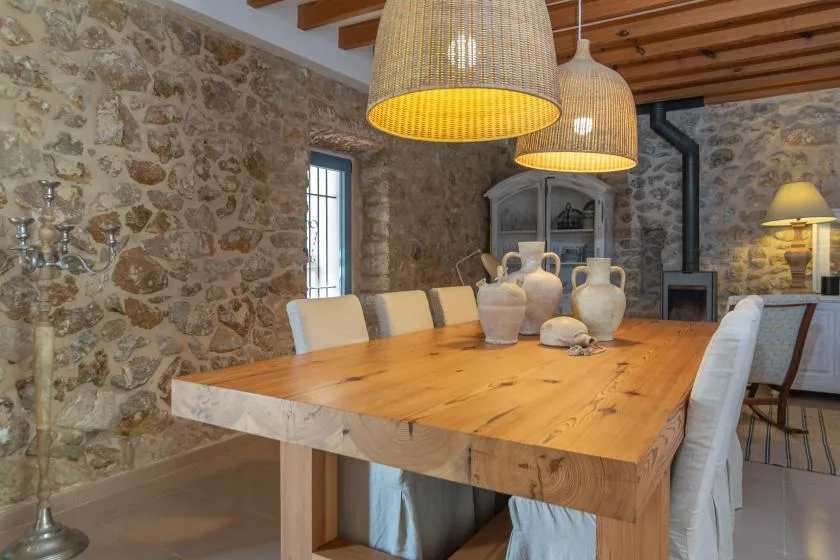 A dining room with a long wooden table, chairs, and stone walls.
