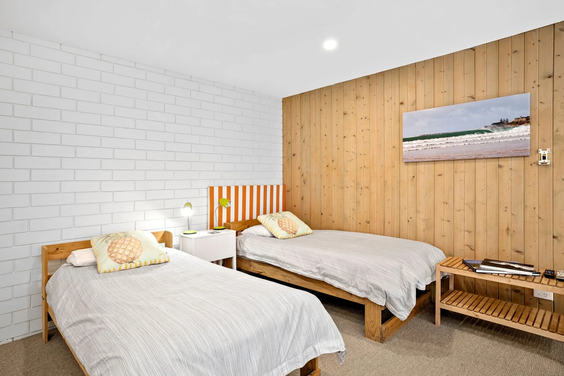 A bedroom with two beds, a nightstand, and a wood-paneled wall.