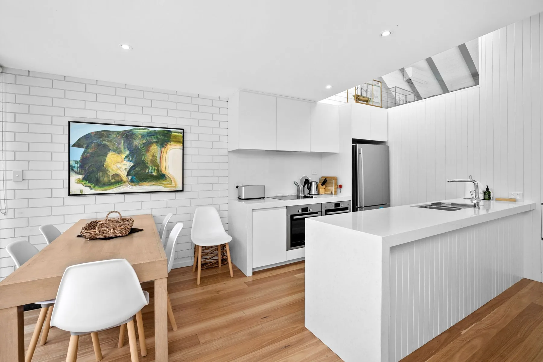 A bright kitchen and dining area with a long counter and wooden table.