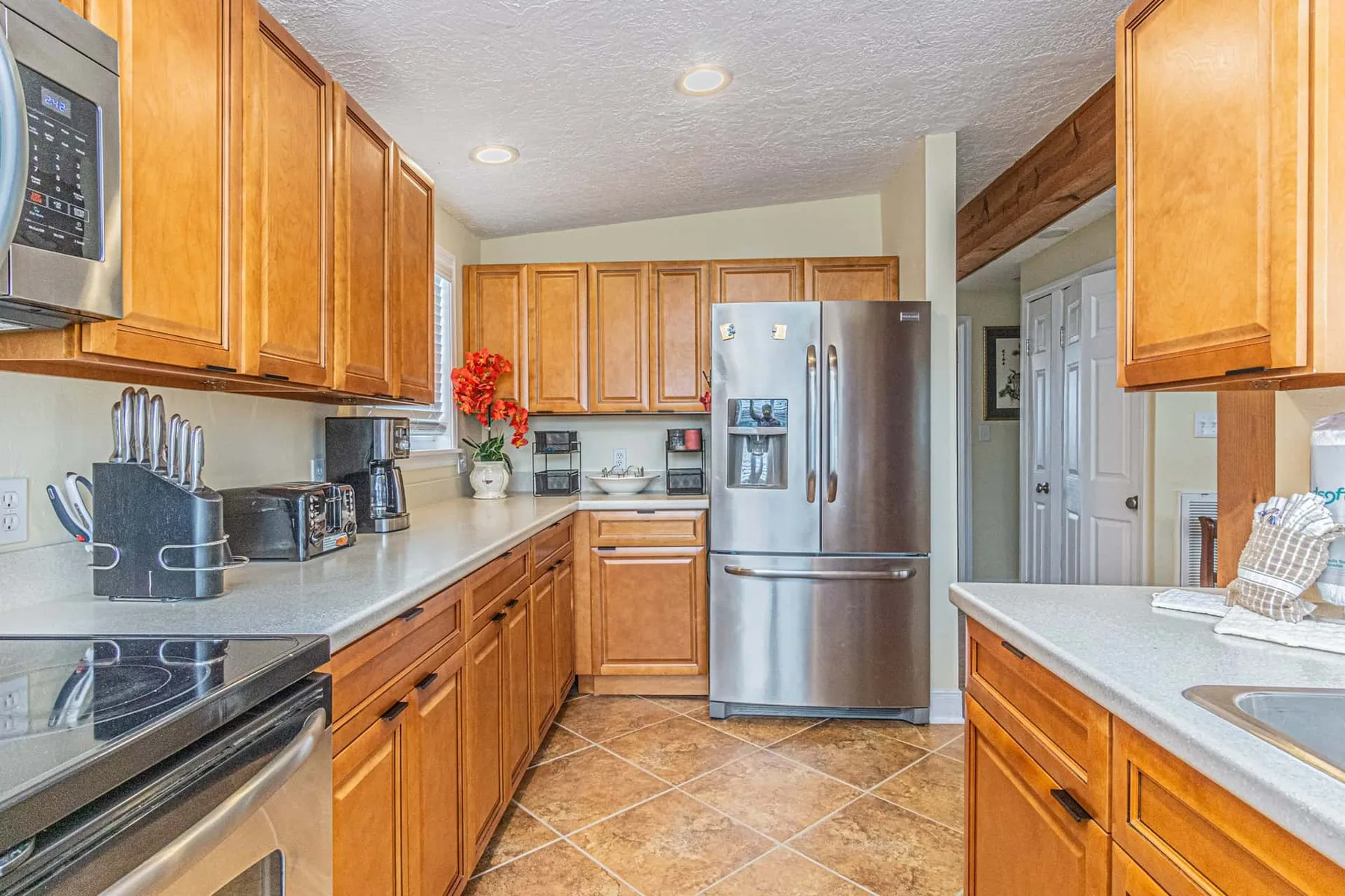A kitchen with wooden cabinets, countertops, and a stainless steel refrigerator.