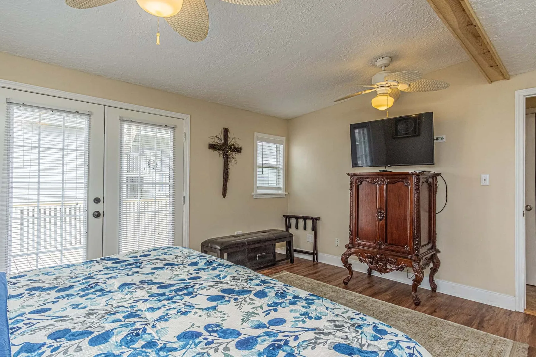 A bedroom with a floral bedspread and a television on a wooden cabinet.