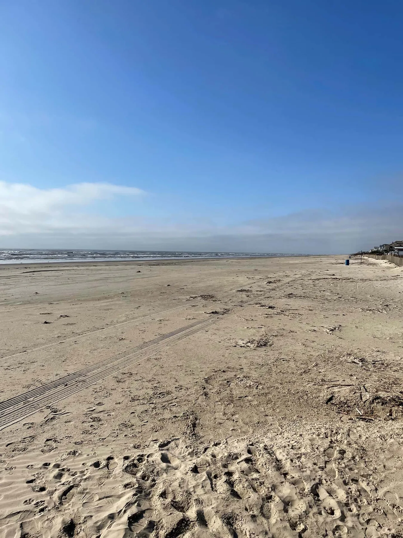A broad sandy beach stretches toward the ocean under a blue sky.