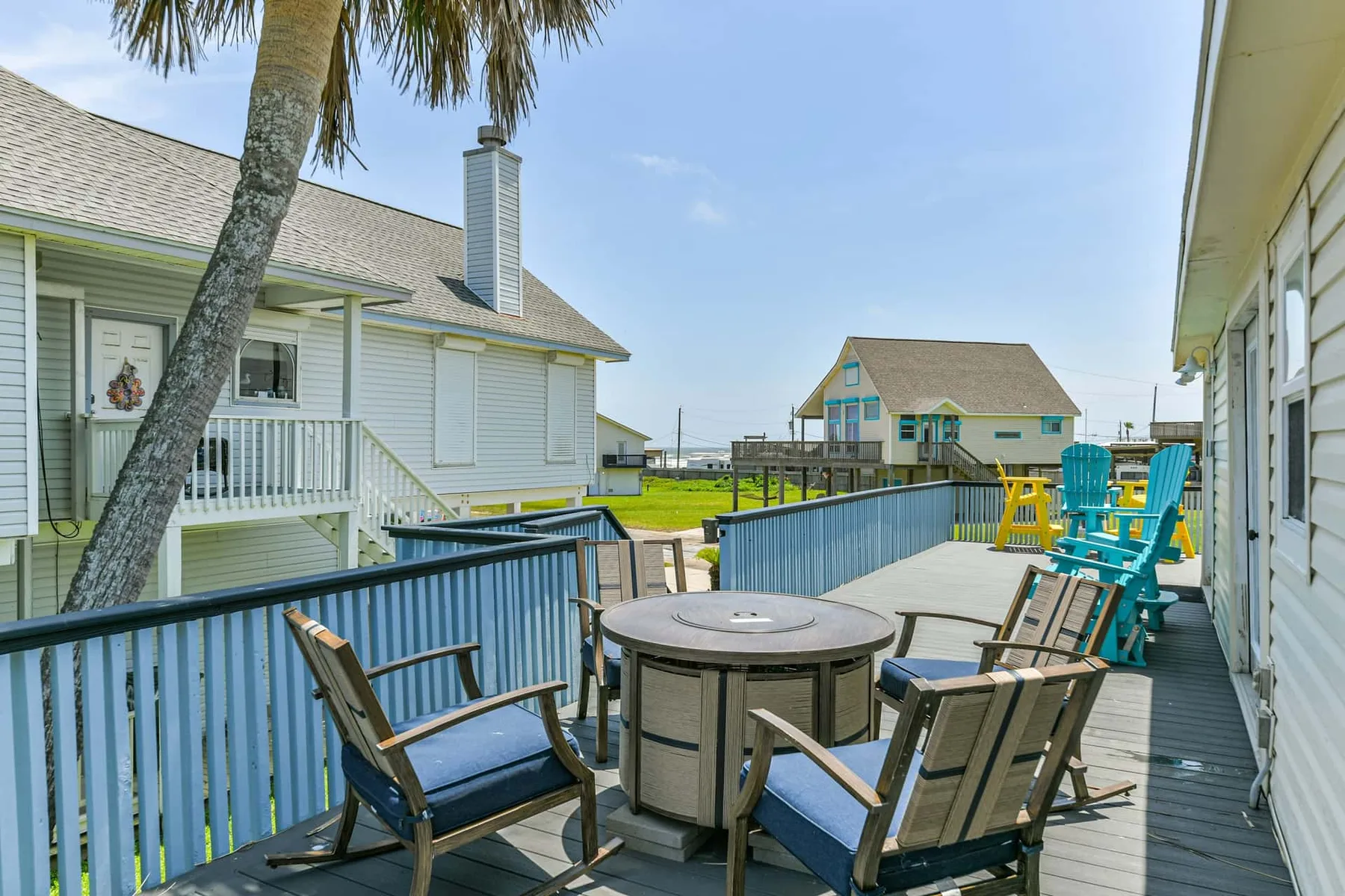 An outdoor deck with seating and a table overlooks neighboring homes and a play area.