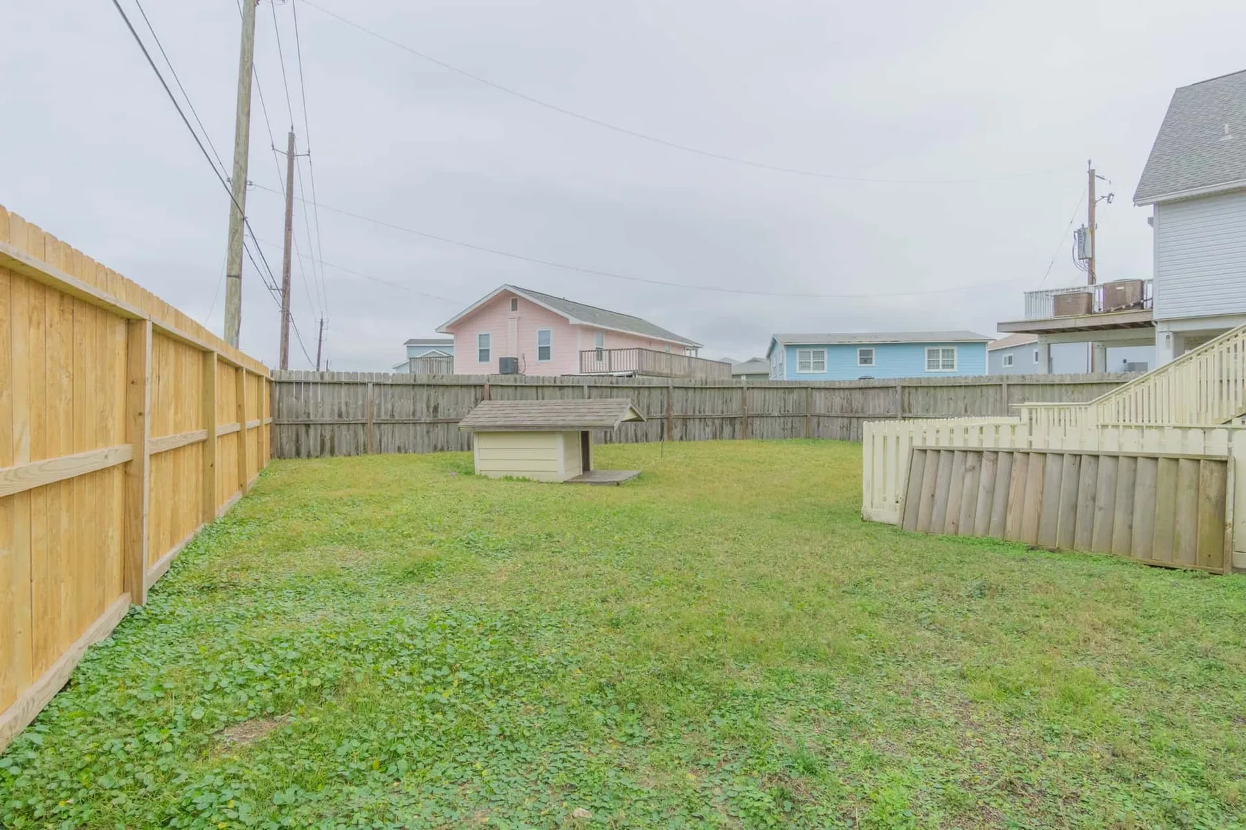 A fenced grassy yard with a small wooden structure near the back.