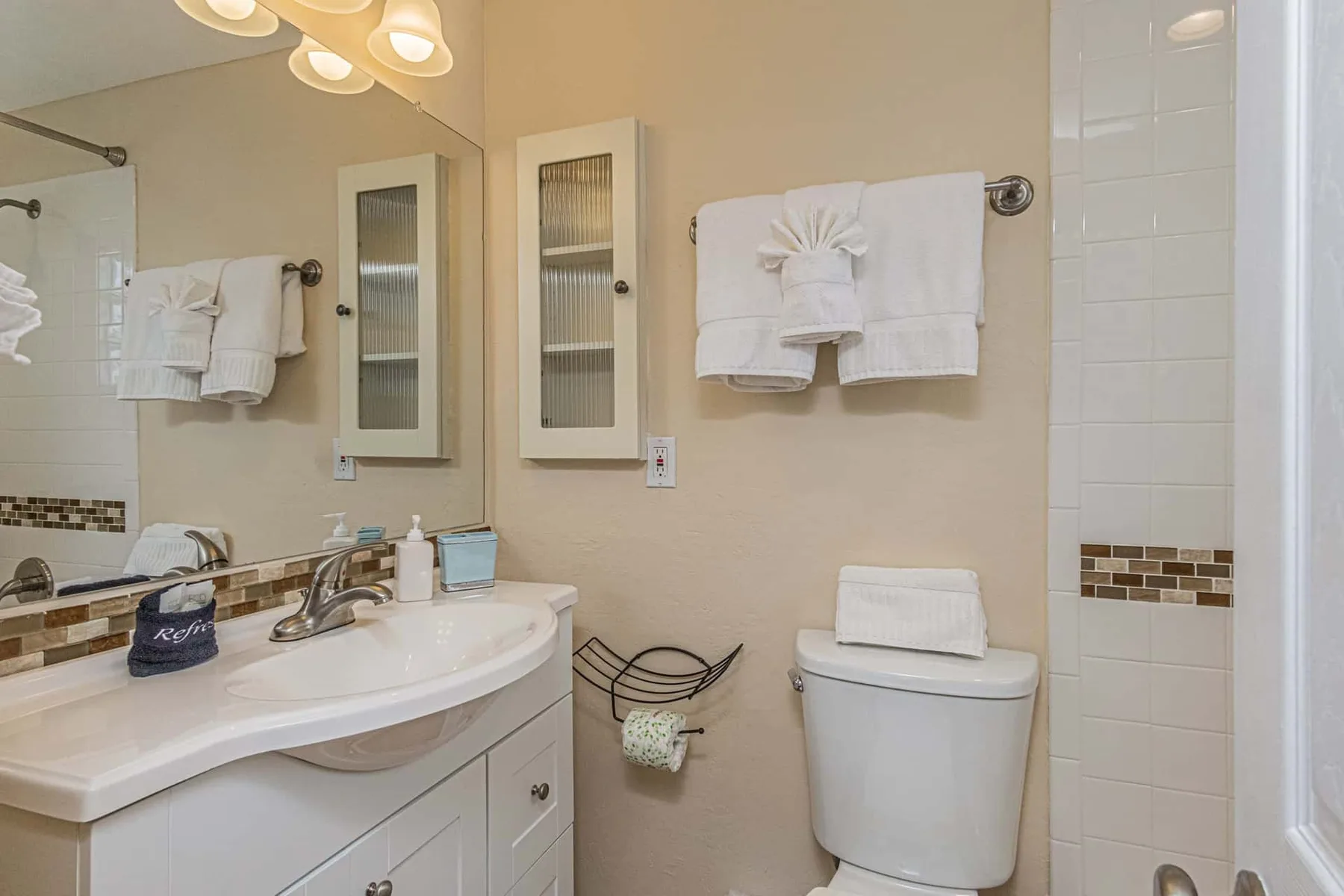 A bathroom with a sink vanity, toilet, and towels hanging on the wall.