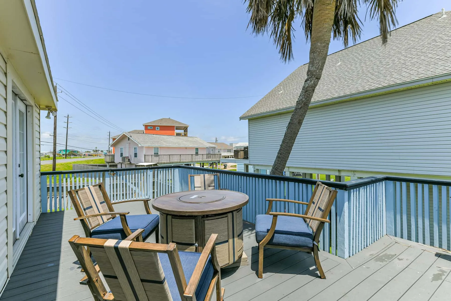 An outdoor deck with seating and a round table overlooks nearby buildings.