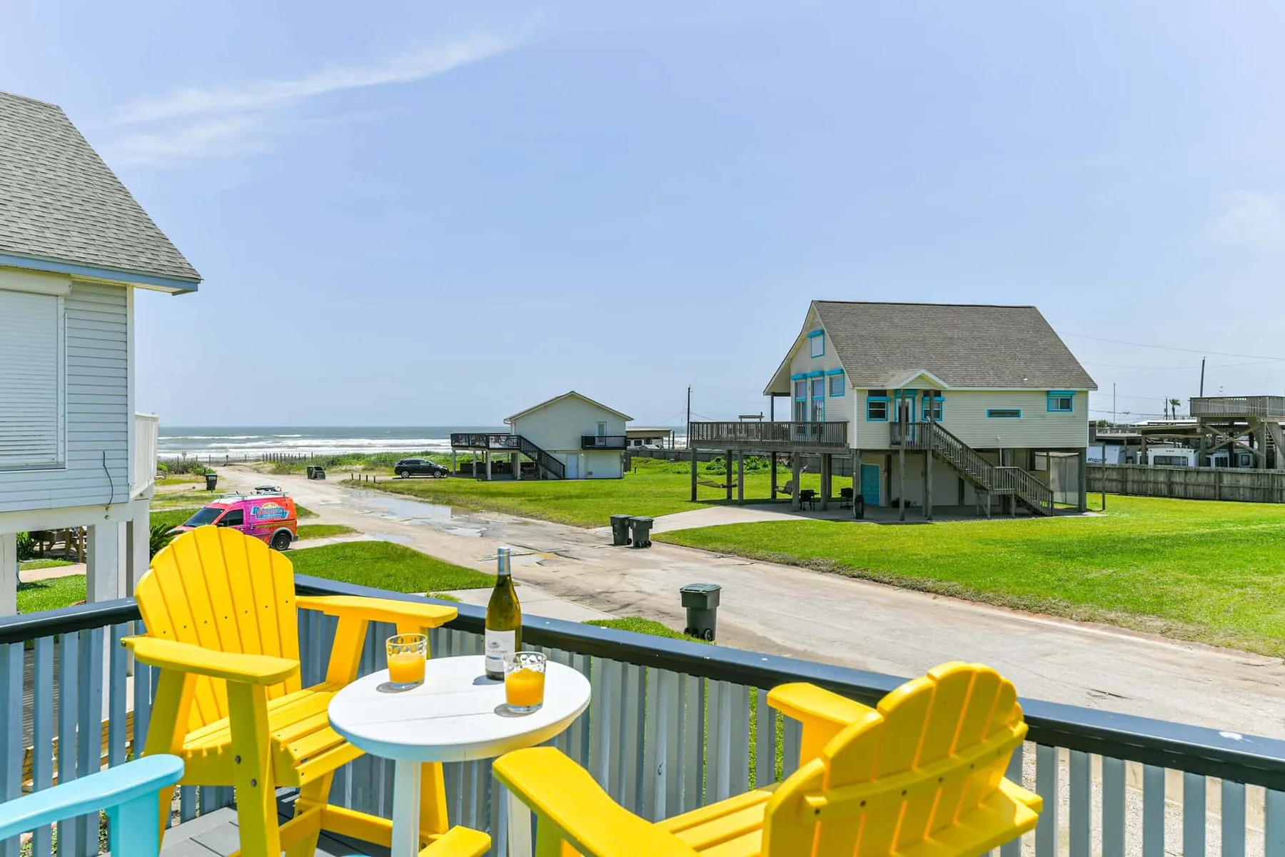 A deck with bright yellow seating overlooks coastal houses and the ocean.