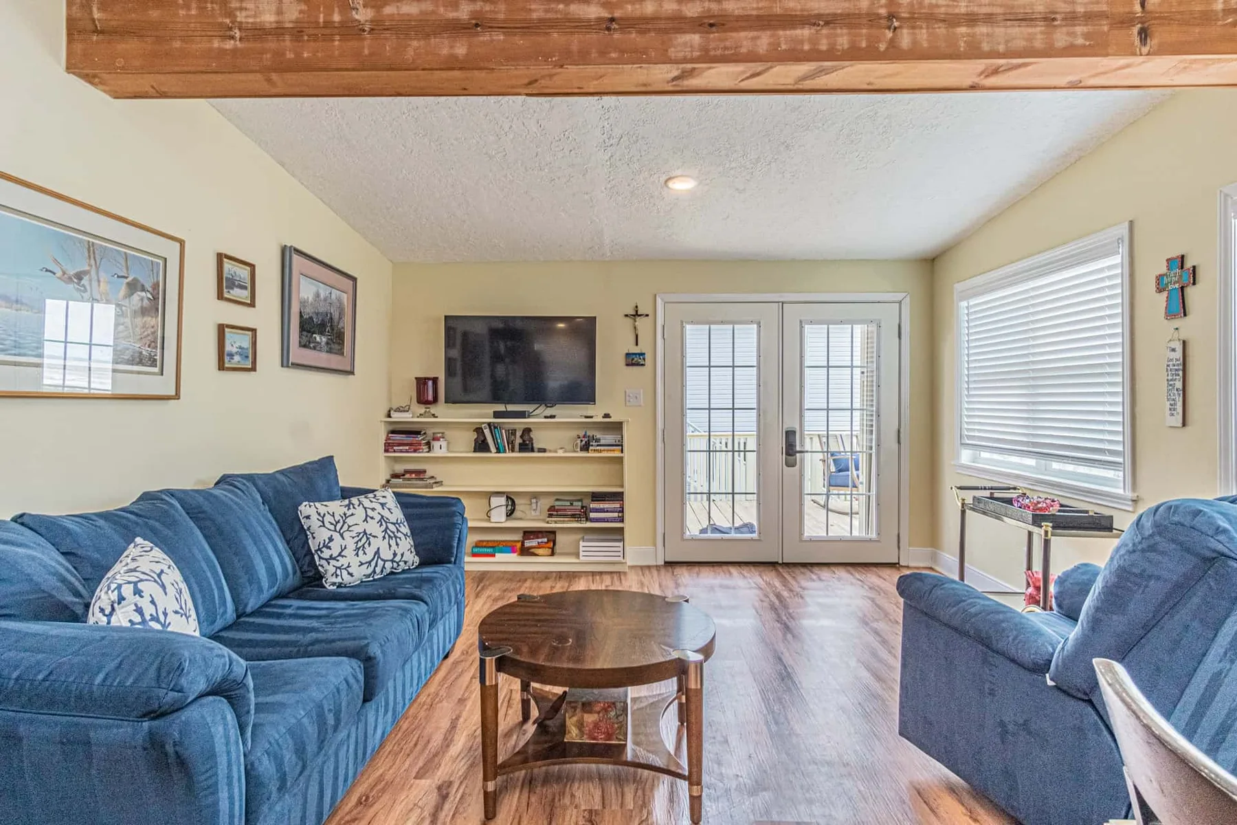 A living room with blue seating, a coffee table, and glass doors.