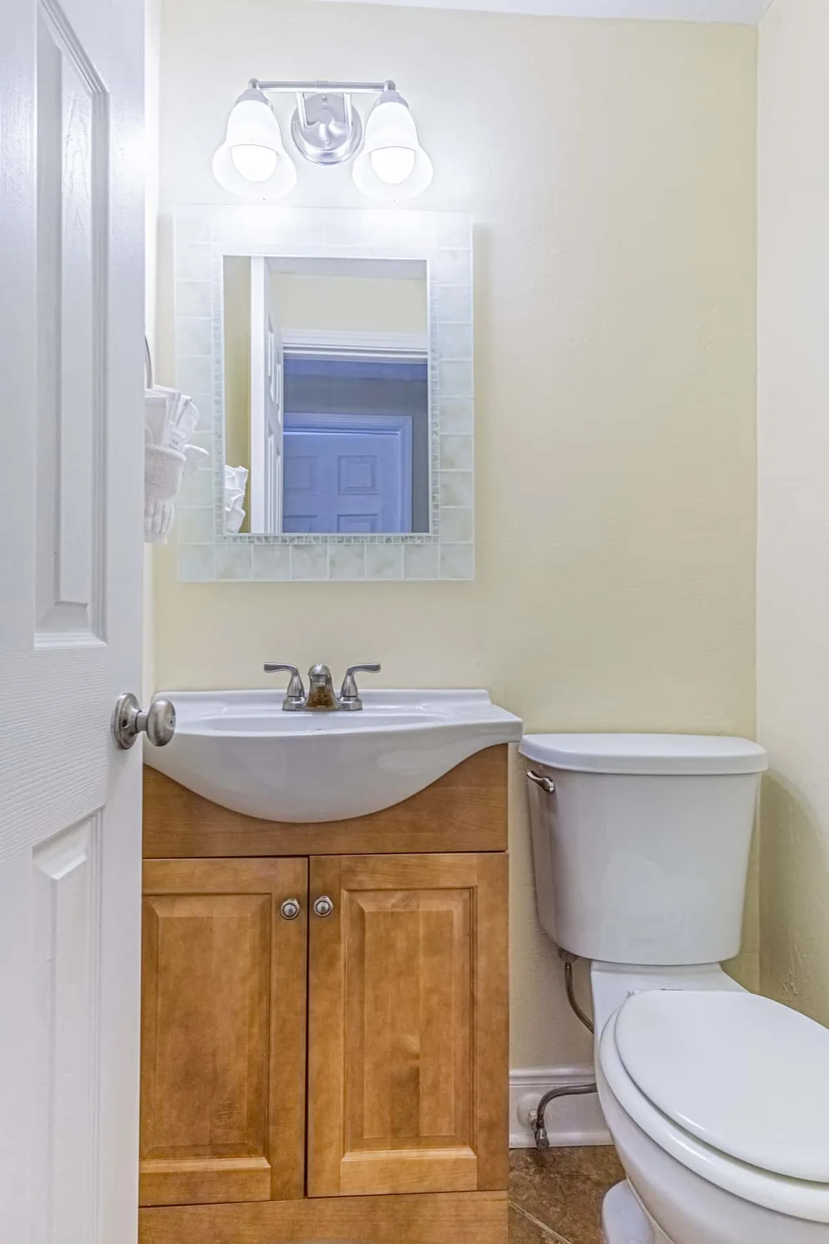A bathroom with a wooden vanity, sink, and toilet beneath a wall mirror.