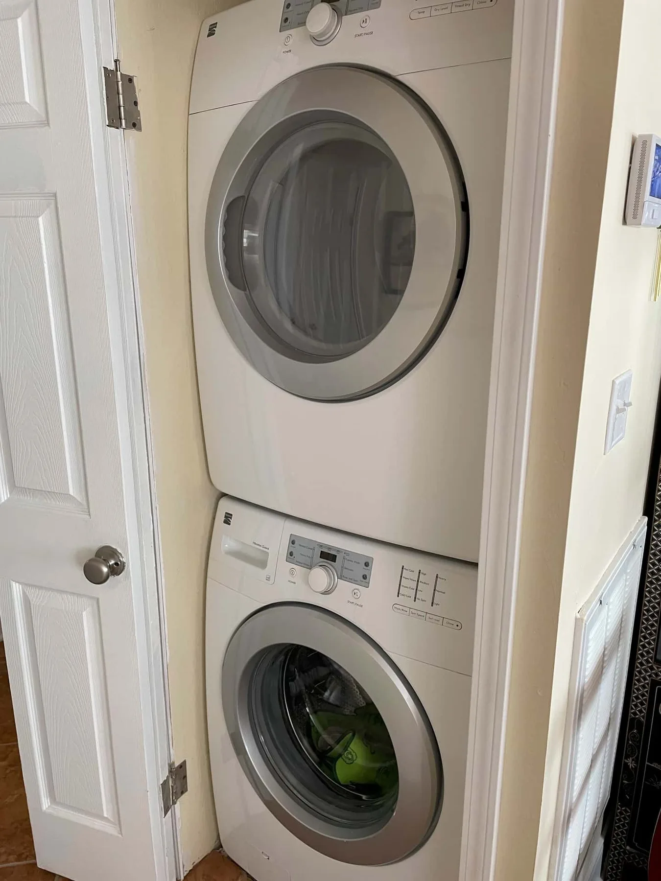A laundry area with a stacked washer and dryer beside a white door.