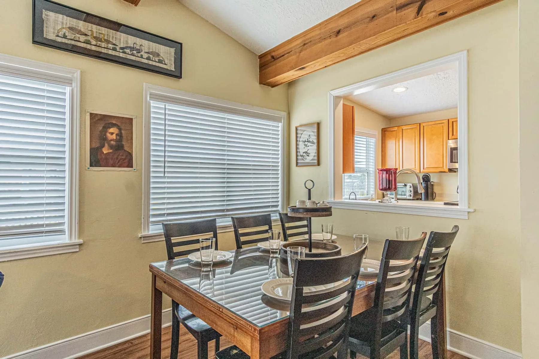 A dining area with a glass-topped table and a pass-through to the kitchen.