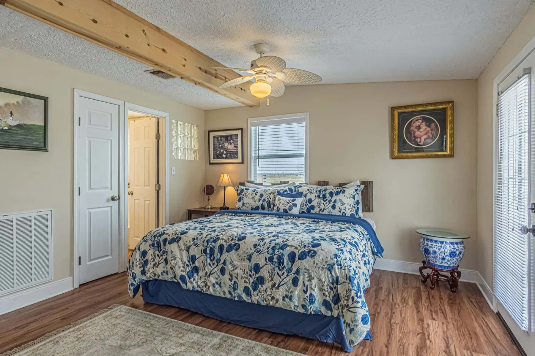 A bedroom with a bed covered in blue floral bedding and a ceiling fan.