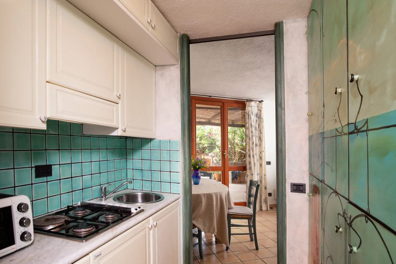 A compact kitchen with turquoise tiled walls and a gas cooktop.