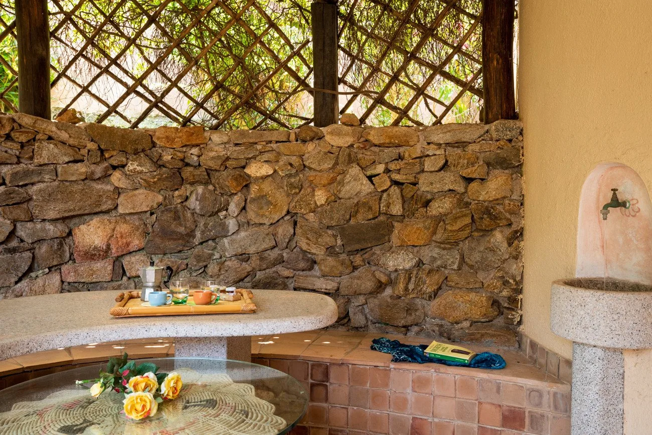 A rustic outdoor dining area with a stone wall and a tiled bench.