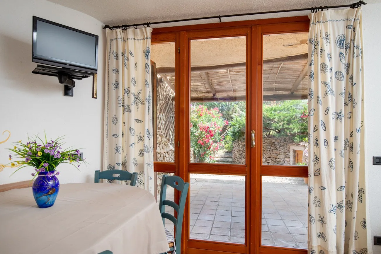 A dining area with a table beside glass doors opening onto a patio.