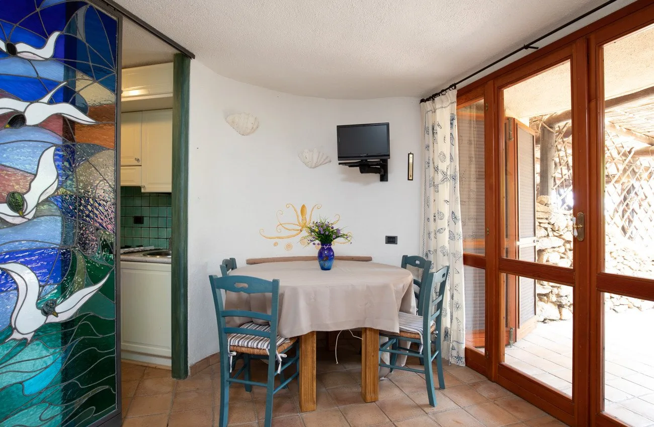 A dining area with a table and chairs beside large glass doors.