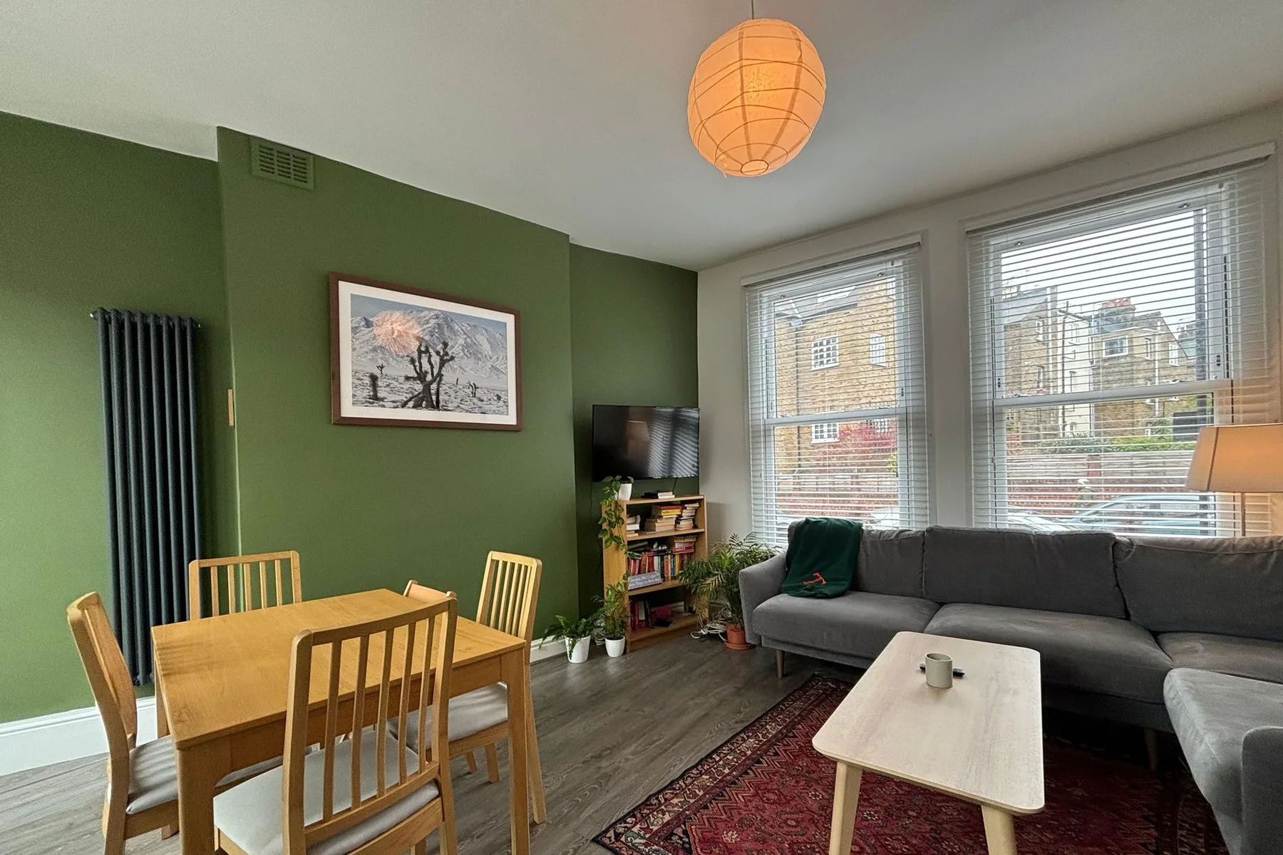 A living room with a dining table, seating, and large windows.
